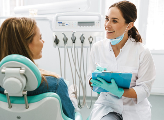 Dentist smiling while taking notes on clipboard